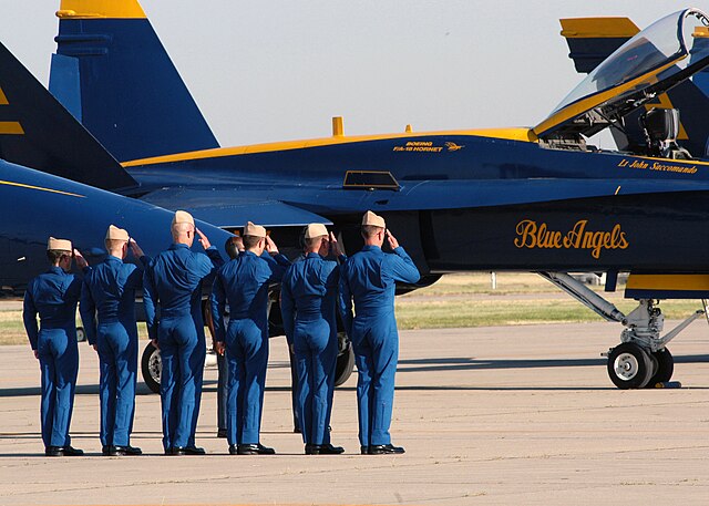 Pilots saluting in front of a Blue Angels jet.