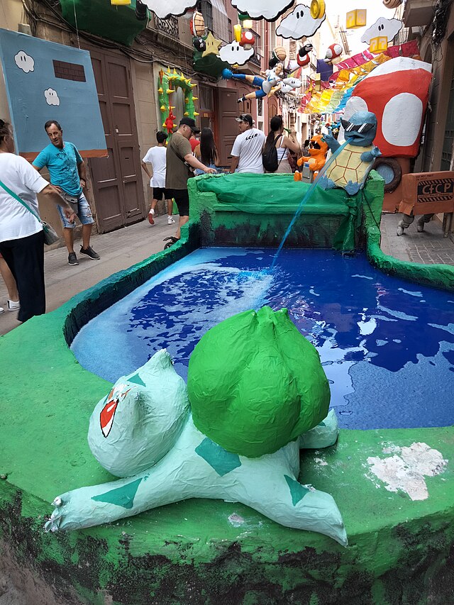 A Bulbasaur sculpture spraying water into a small festival fountain.