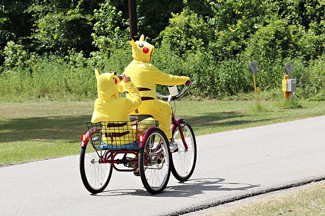 Two people riding a bike wearing Pikachu costumes.